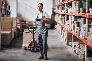 Warehouse Workers Pulling A Pallet Truck WIth Two Open Cardboard Boxes